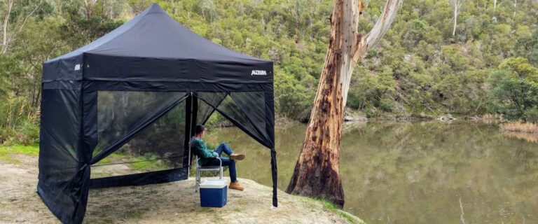 Altegra camping gazebo with mesh walls sitting by the river - mesh gazebo walls increase your family's protection when camping.