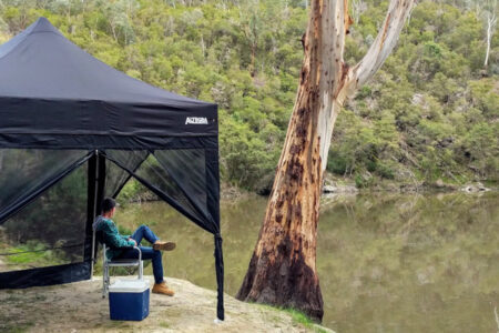 Altegra camping gazebo with mesh walls sitting by the river - mesh gazebo walls increase your family's protection when camping.